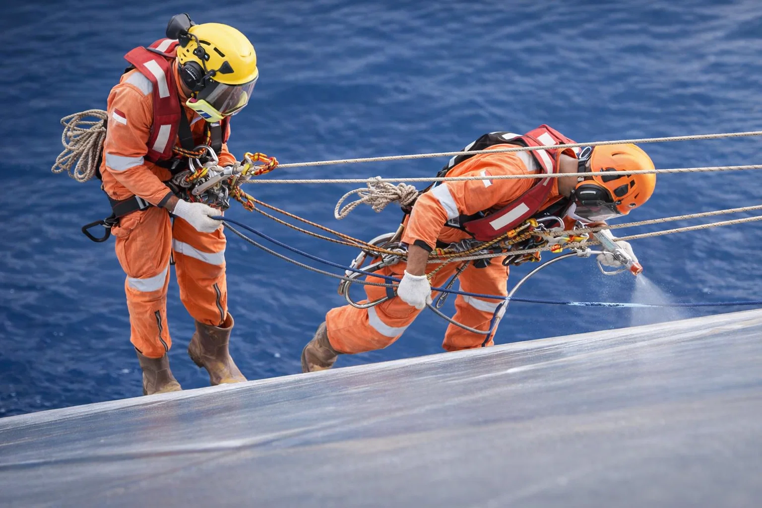 Technician operating an ultra-high-pressure water jetting lance against a ship hull